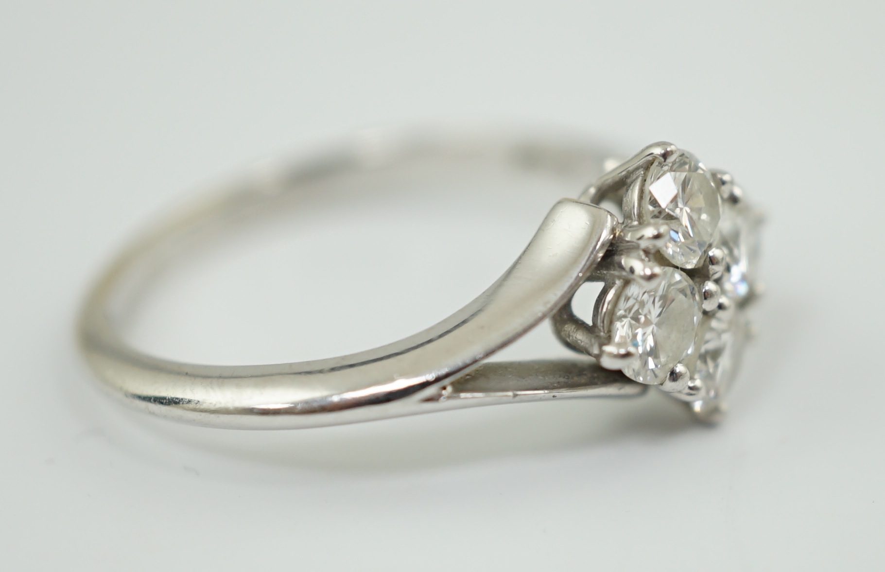 A modern platinum and four stone diamond cluster set ring